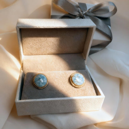 Pair of earrings in a decorative box with a ribbon on a soft fabric background