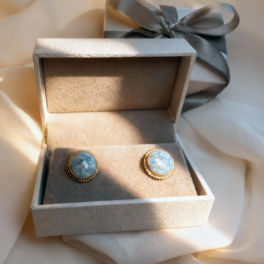 Pair of earrings in a decorative box with a ribbon on a soft fabric background